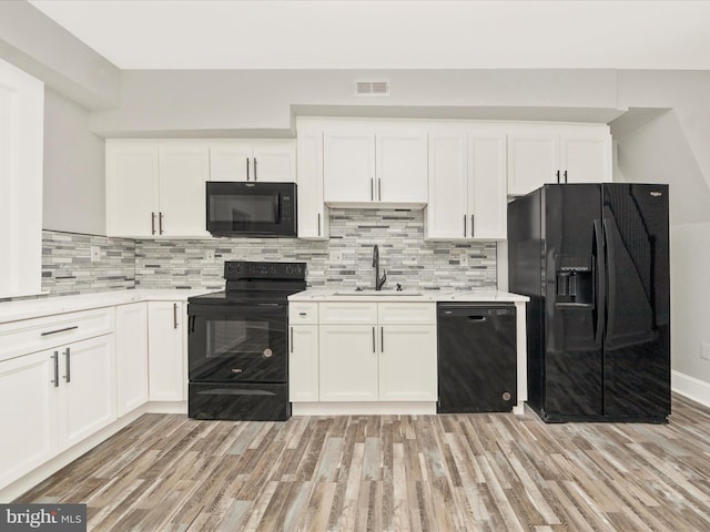 kitchen with black appliances, light wood-type flooring, visible vents, and a sink