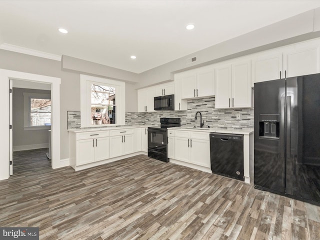 kitchen with backsplash, white cabinetry, black appliances, and light countertops