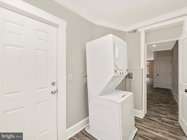 washroom featuring visible vents, crown molding, baseboards, dark wood finished floors, and stacked washing maching and dryer