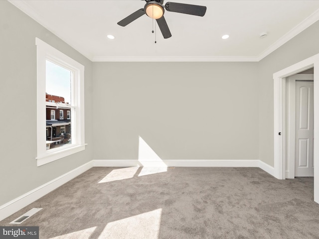 carpeted empty room with visible vents, crown molding, and baseboards