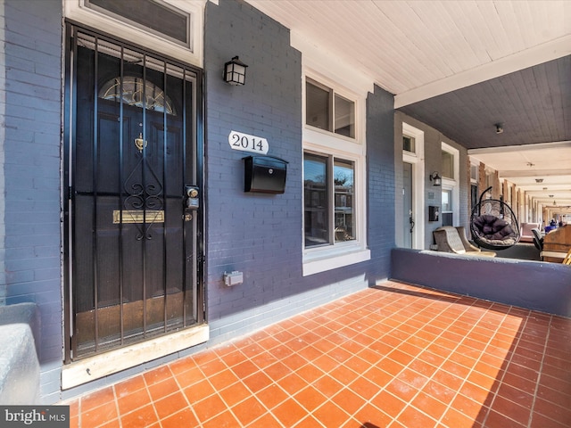 entrance to property featuring covered porch and brick siding