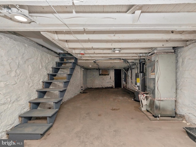 unfinished below grade area featuring stairway, heating unit, and water heater