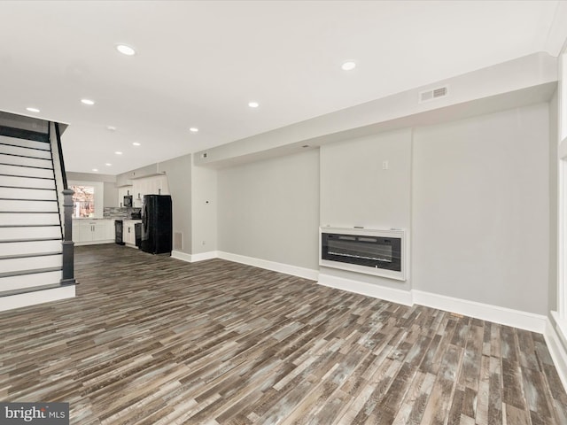 unfurnished living room with heating unit, stairway, recessed lighting, and dark wood-style flooring