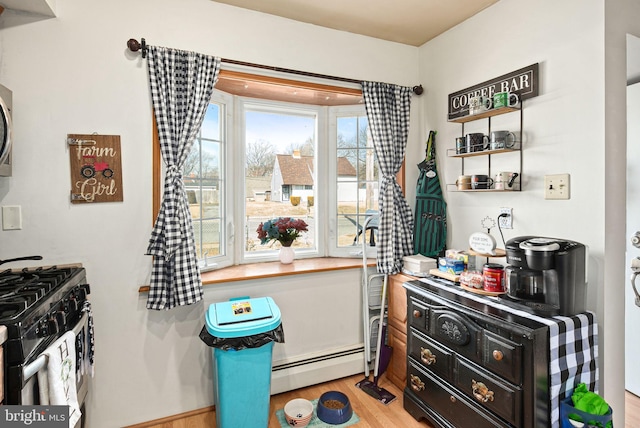 interior space with stainless steel gas range oven, a baseboard radiator, dark cabinetry, and light wood-style floors