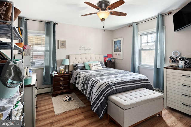 bedroom featuring a baseboard radiator, a ceiling fan, and wood finished floors