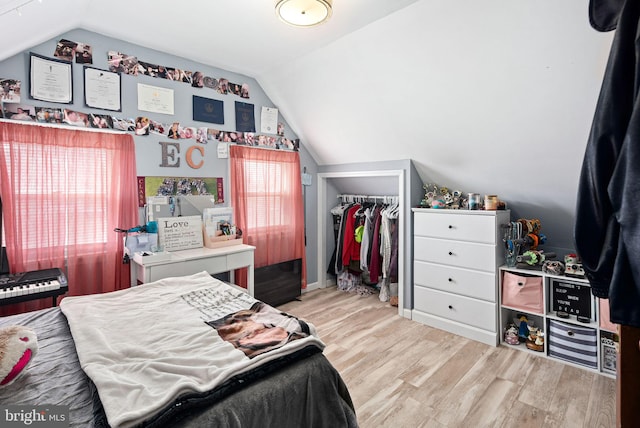 bedroom with light wood-style floors, a closet, and vaulted ceiling