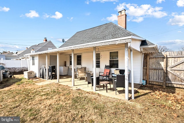 back of house with a patio area, a shingled roof, a chimney, and a yard