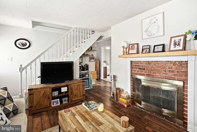 living area with dark wood-style flooring, stairway, and a fireplace