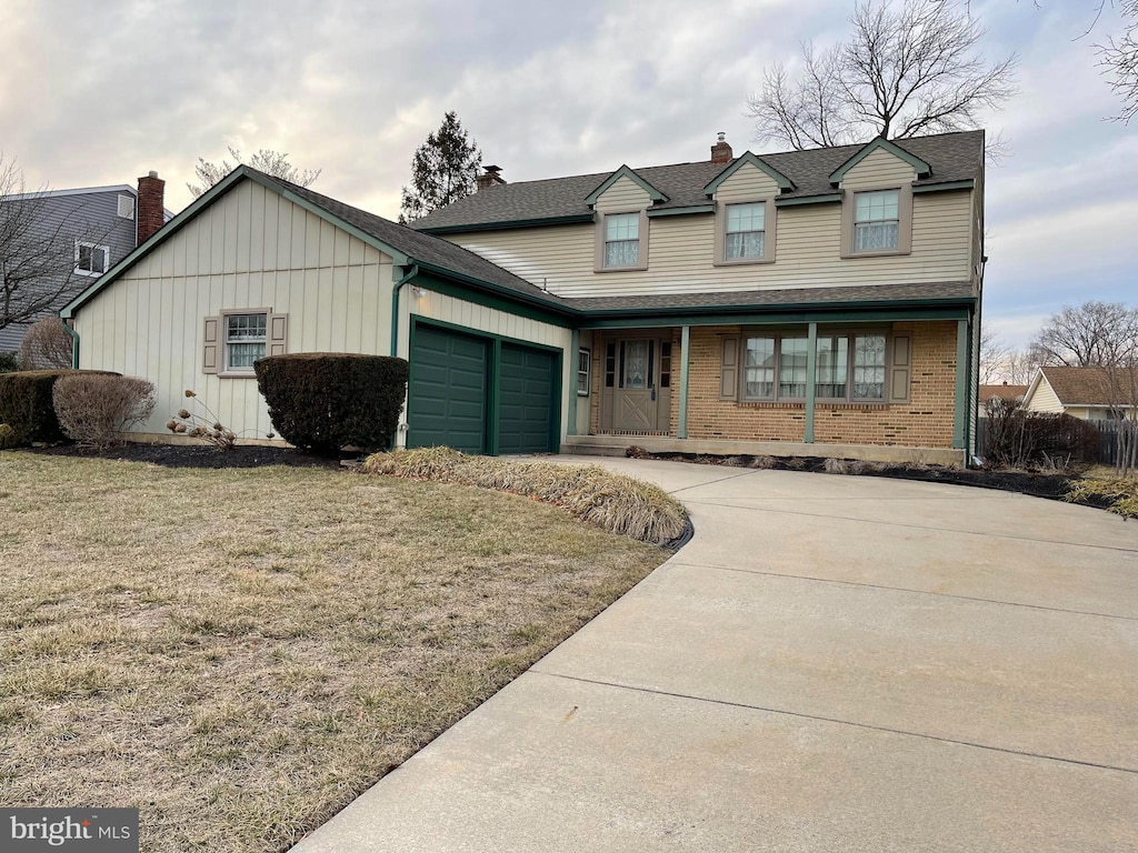 traditional home with brick siding, a chimney, an attached garage, driveway, and a front lawn