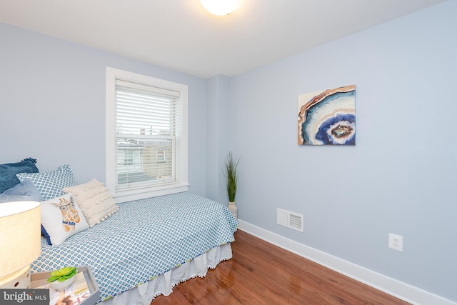 bedroom featuring baseboards, visible vents, and wood finished floors