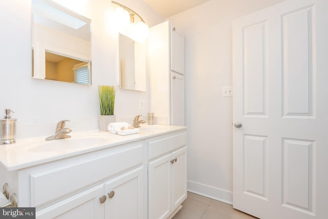 bathroom with double vanity, tile patterned flooring, baseboards, and a sink