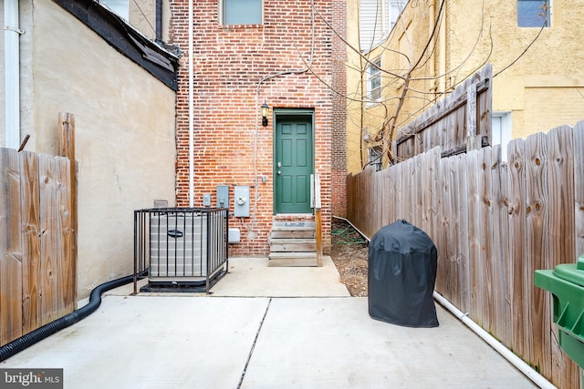 entrance to property featuring a patio area, brick siding, and fence