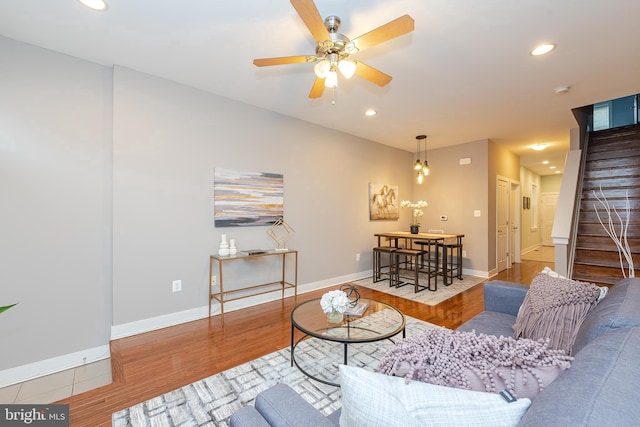 living area featuring light wood-style floors, baseboards, and stairway