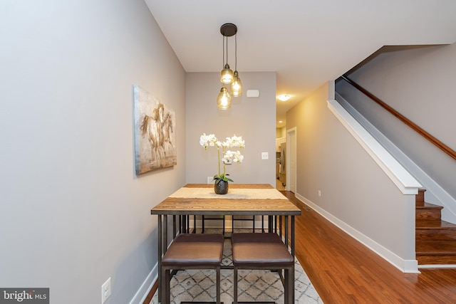 dining space featuring stairs, baseboards, and wood finished floors