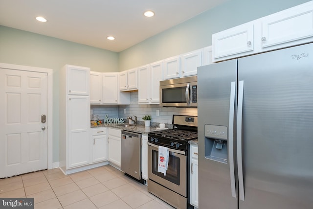 kitchen with stainless steel appliances, light tile patterned floors, white cabinets, and tasteful backsplash