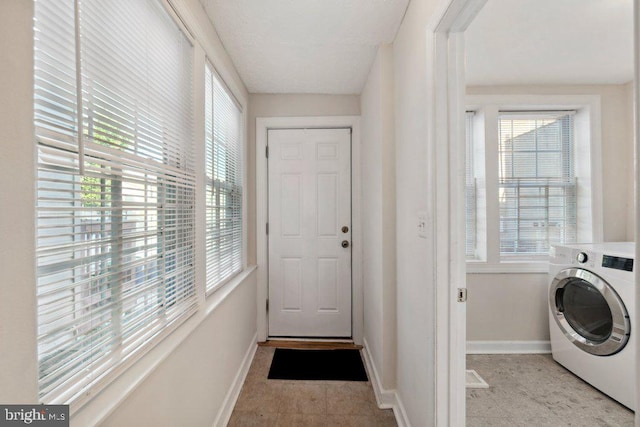 clothes washing area featuring washer / dryer, baseboards, laundry area, and a wealth of natural light