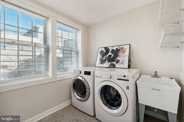 laundry area with laundry area, baseboards, a sink, and independent washer and dryer