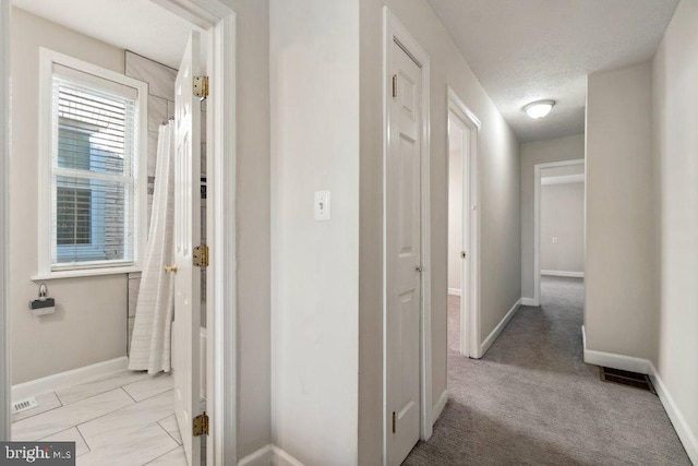 hall featuring visible vents, baseboards, and a textured ceiling