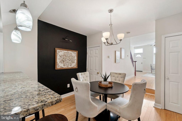 dining room featuring a notable chandelier, light wood-style flooring, and baseboards