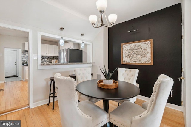 dining area featuring baseboards, light wood finished floors, visible vents, and a notable chandelier