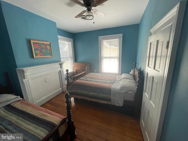 bedroom with multiple windows, ceiling fan, and hardwood / wood-style floors