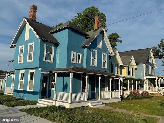 view of front of home with a front lawn, a porch, and a chimney