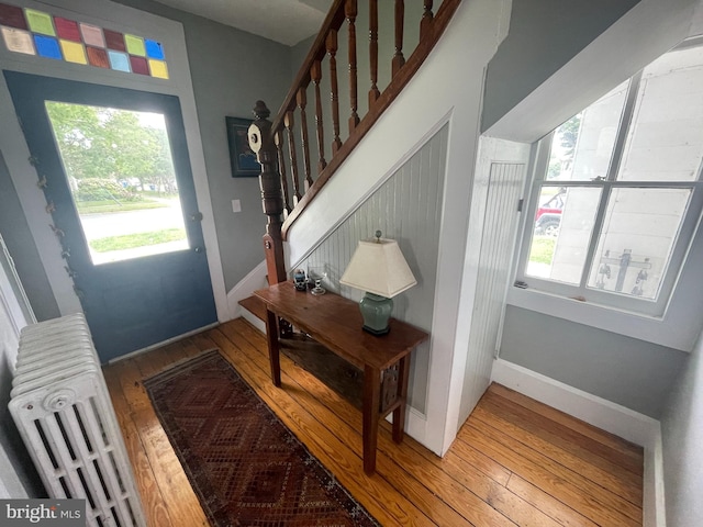 entryway featuring stairway, radiator heating unit, baseboards, and wood-type flooring