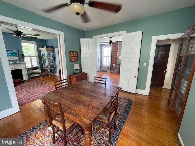 dining area featuring hardwood / wood-style floors, baseboards, radiator, and ceiling fan