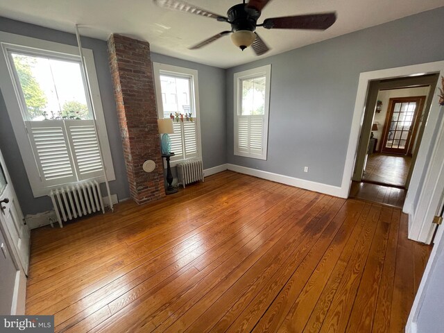 empty room featuring radiator heating unit, a ceiling fan, and hardwood / wood-style flooring