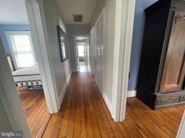 corridor with baseboards, wood-type flooring, and visible vents