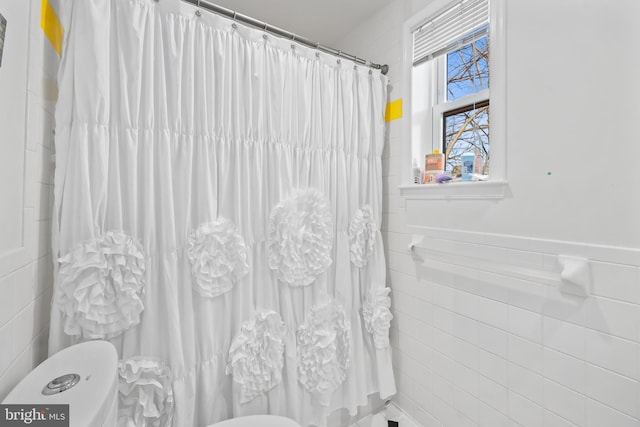 full bathroom with a shower with curtain, toilet, tile walls, and a wainscoted wall