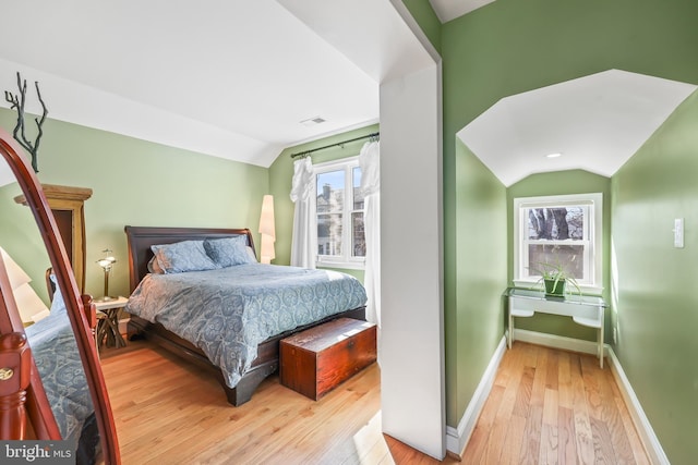 bedroom featuring vaulted ceiling, hardwood / wood-style flooring, visible vents, and baseboards