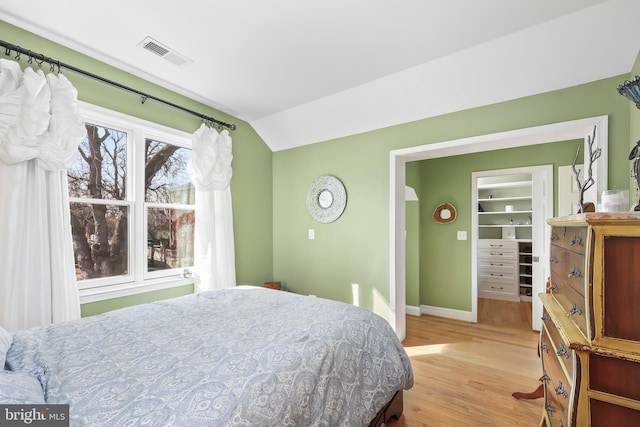 bedroom featuring visible vents, lofted ceiling, light wood-style floors, and baseboards