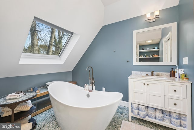 bathroom featuring baseboards, lofted ceiling with skylight, a soaking tub, and vanity