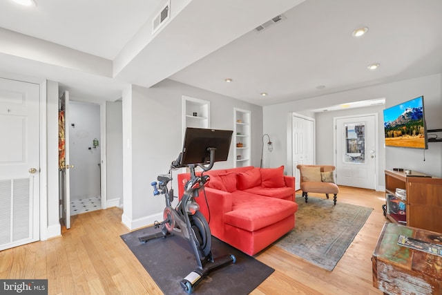 workout area featuring built in features, visible vents, baseboards, and wood finished floors