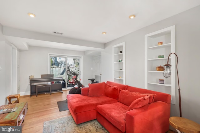 living area with visible vents, built in shelves, baseboards, light wood-type flooring, and recessed lighting