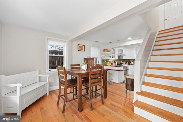 dining space featuring stairway, baseboards, and light wood-style floors