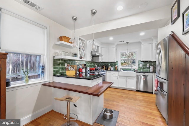 kitchen featuring visible vents, dark countertops, stainless steel appliances, a peninsula, and white cabinets