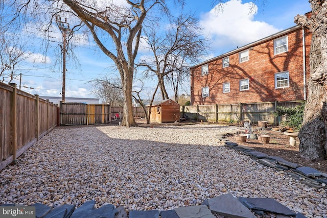 view of yard with an outbuilding, a shed, a fenced backyard, and a gate