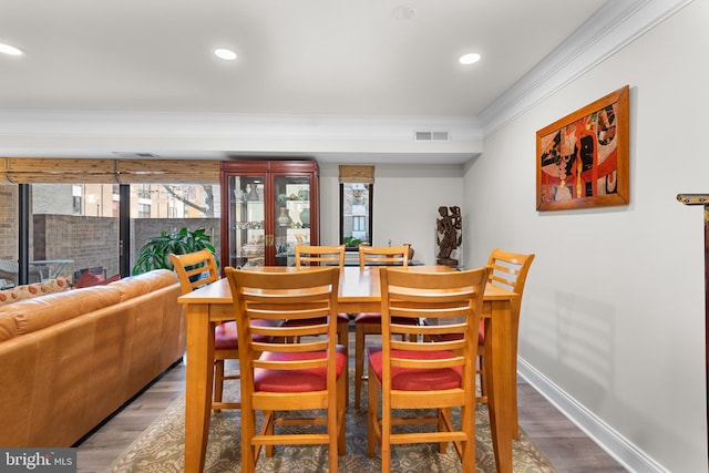 dining space featuring ornamental molding, wood finished floors, visible vents, and baseboards