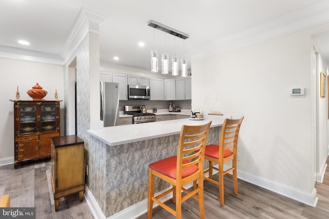 kitchen featuring appliances with stainless steel finishes, light countertops, a peninsula, and a breakfast bar area