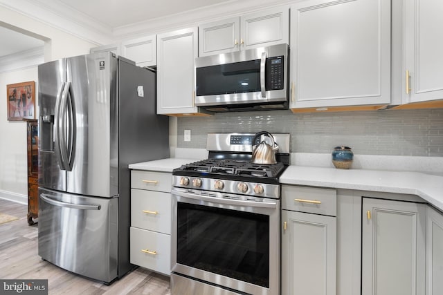 kitchen featuring stainless steel appliances, decorative backsplash, light wood-style flooring, and crown molding