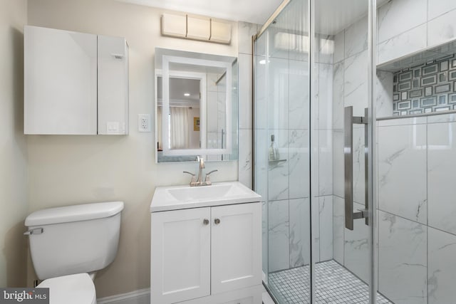 bathroom featuring toilet, a marble finish shower, and vanity