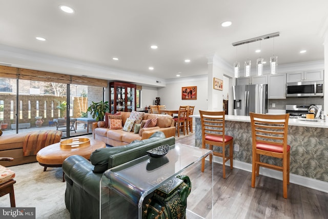 living room featuring ornamental molding, recessed lighting, light wood-style flooring, and baseboards