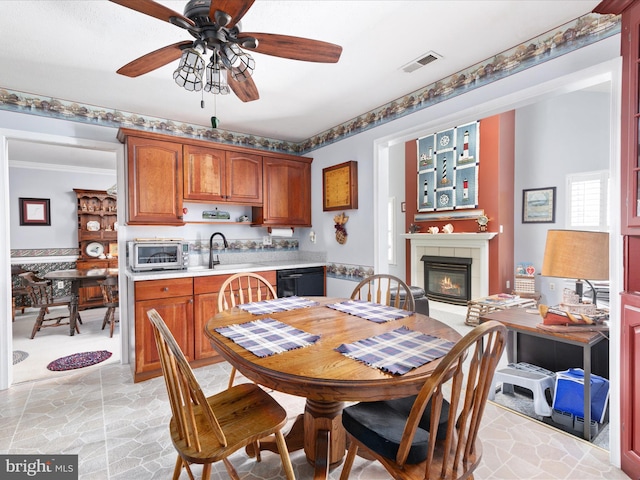 dining area with crown molding, visible vents, a ceiling fan, stone finish floor, and a tile fireplace