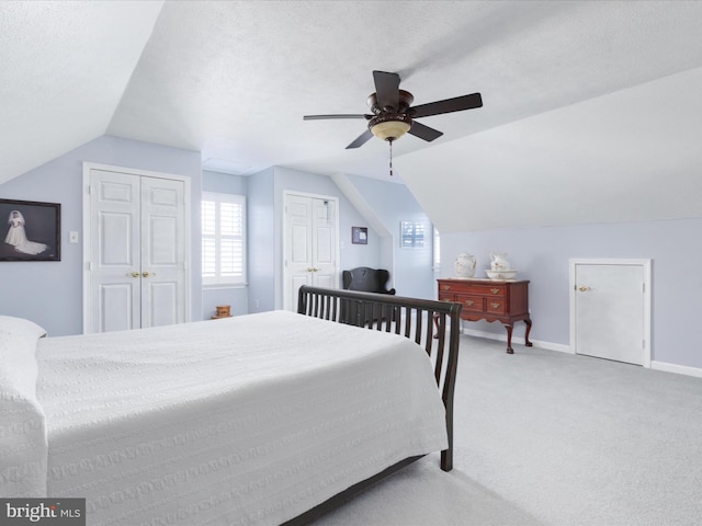 carpeted bedroom with vaulted ceiling, a textured ceiling, baseboards, and ceiling fan