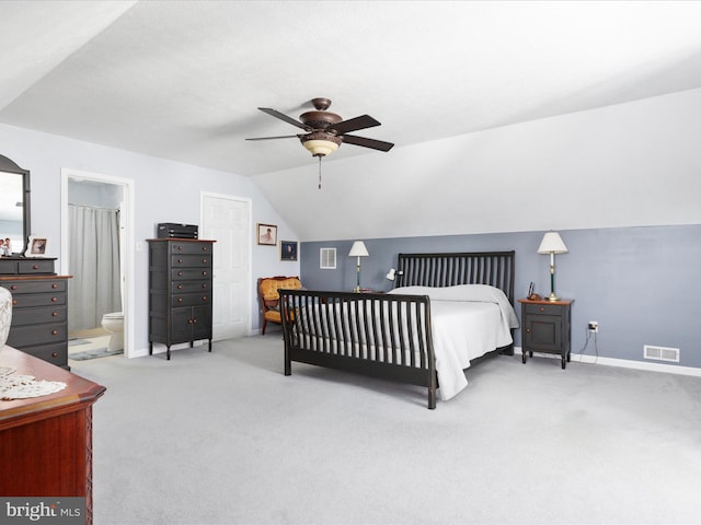 carpeted bedroom featuring lofted ceiling, visible vents, ceiling fan, ensuite bath, and baseboards