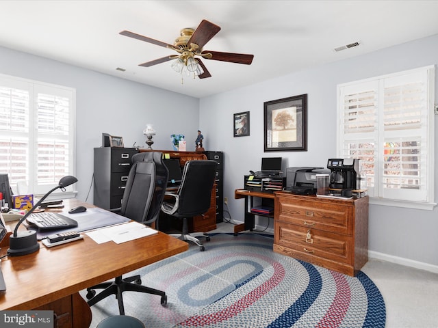 office space with baseboards, visible vents, a ceiling fan, and light colored carpet