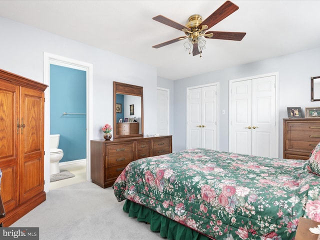 bedroom with multiple closets, light colored carpet, connected bathroom, and ceiling fan