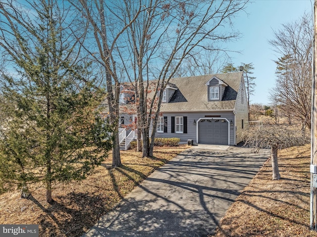 new england style home featuring aphalt driveway, roof with shingles, and a garage